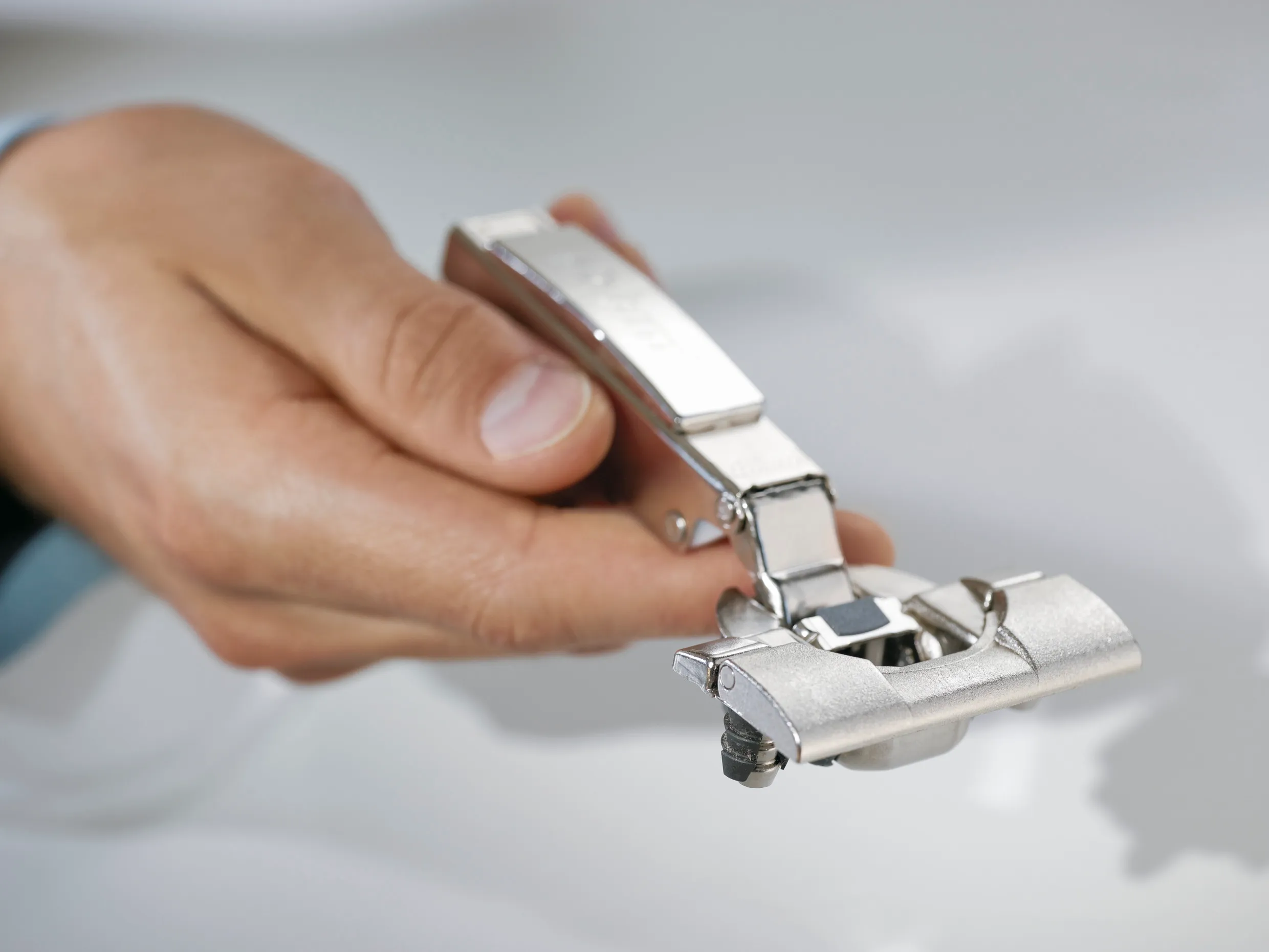 Blum CLIP top BLUMOTION Topfscharnier mit Montageplatte in der Hand, Scharnierarm geöffnet