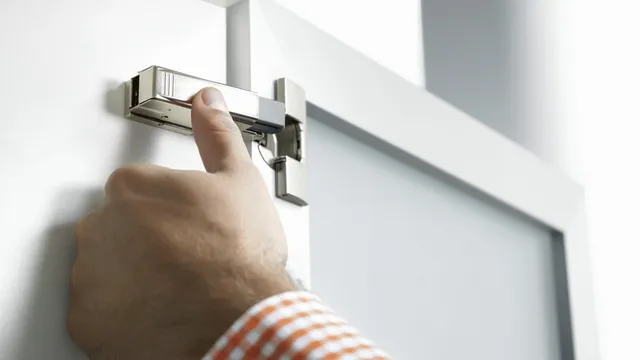 Hand drückt das BLUMOTION 973A Aufsteckteil auf den Scharnierarm eines Blum CLIP top Scharniers an einer weißen Schranktür