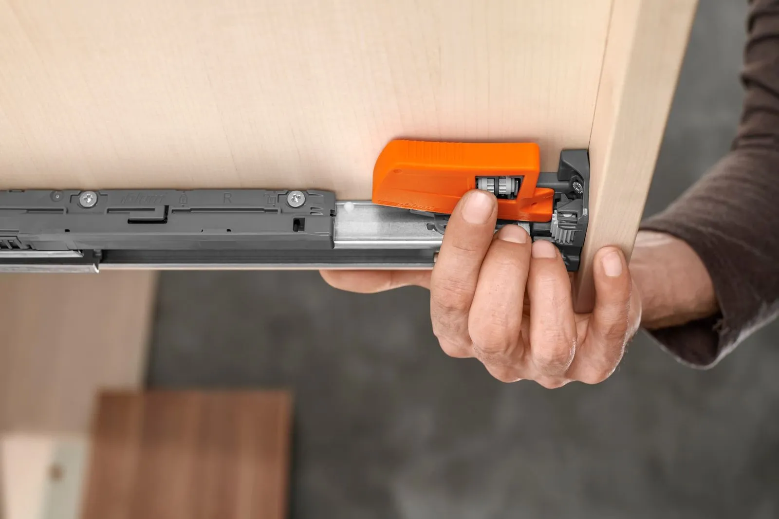 Orange Rastkupplung klickt vorne unter dem Holzschubkasten in die MOVENTO-Schiene ein