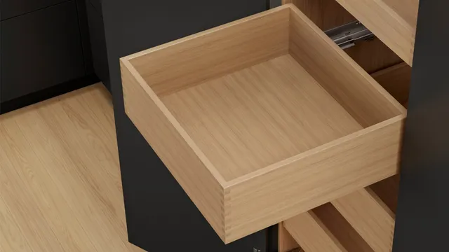 Ausgezogener Holzschubkasten aus Eiche mit sichtbarer Fingerzinkung an der Ecke, auf einer Metallschiene im dunklen Korpus
