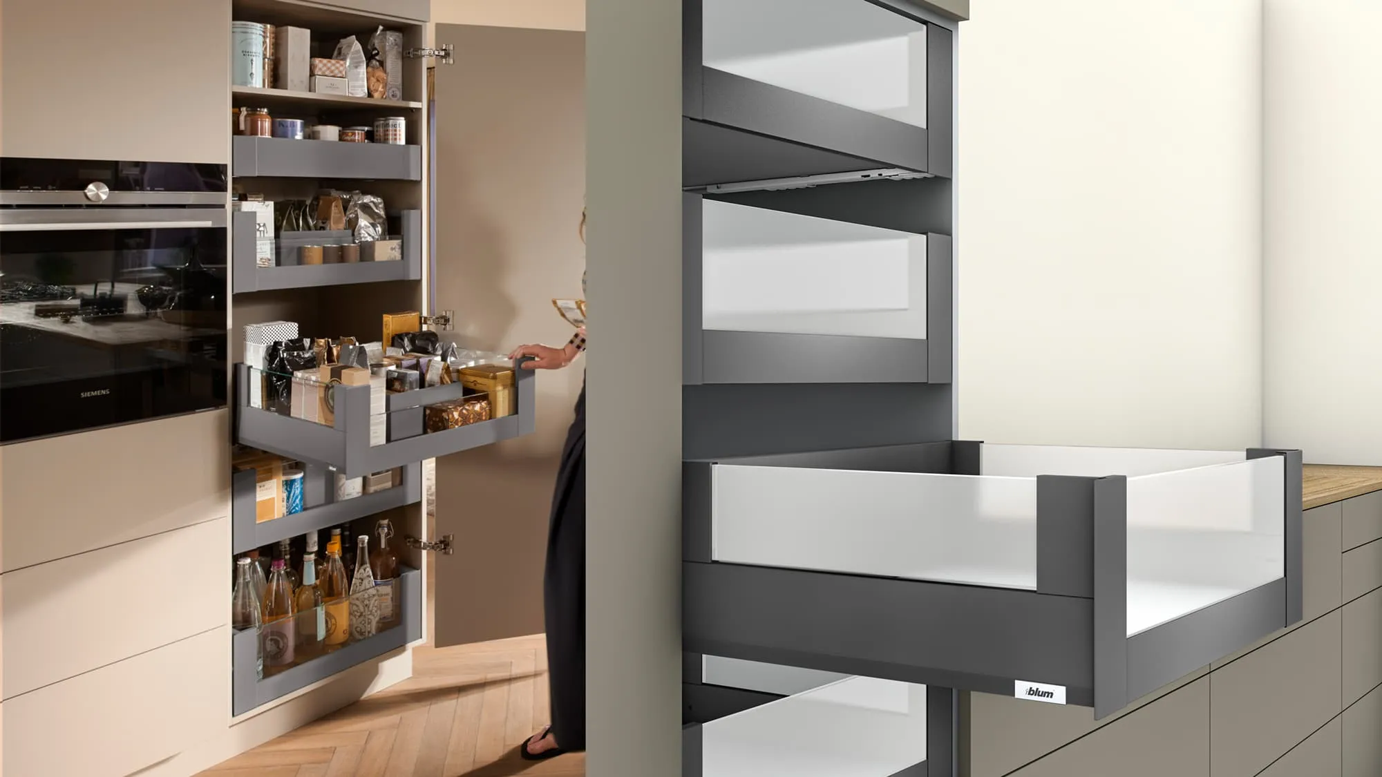 Geöffneter SPACE TOWER Vorratsschrank mit gefüllten MERIVOBOX-Innenauszügen, rechts daneben ein hoher Innenauszug mit Glas-Designelement