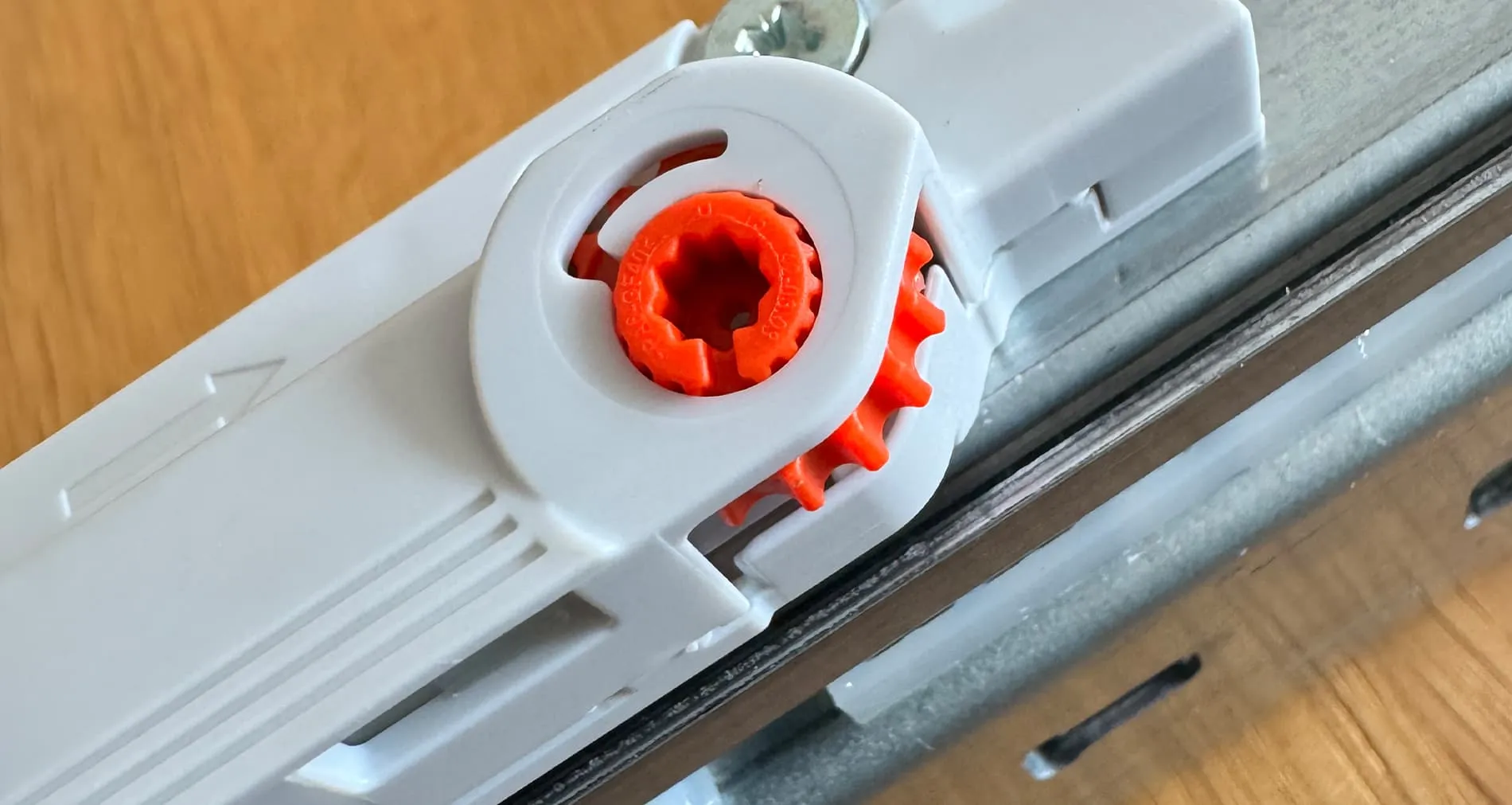 Detailaufnahme des orangen Verstellrads an der reinen MOVENTO TIP-ON-Schiene