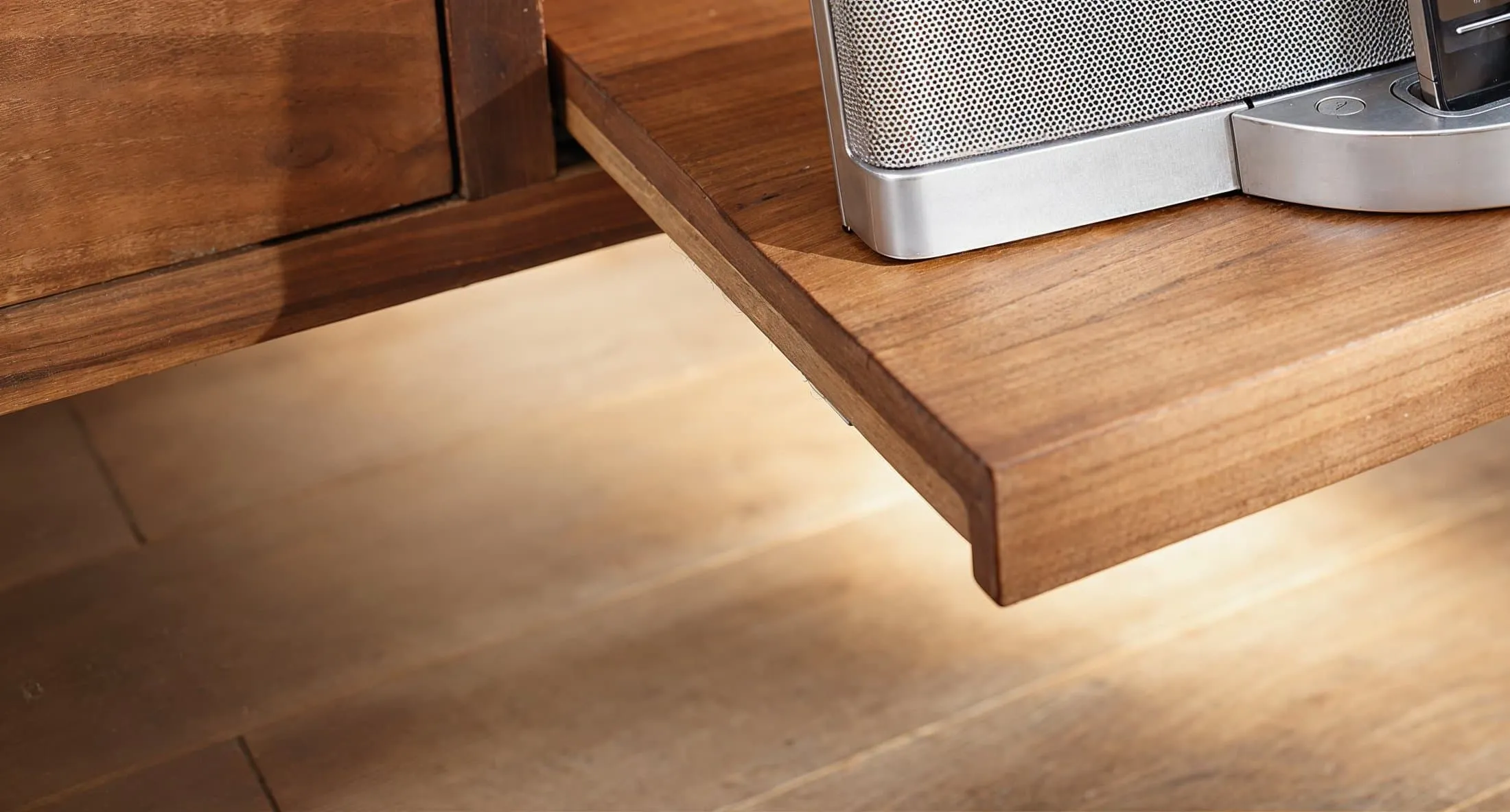 Ausgezogenes Holztablar aus einem Sideboard mit Lautsprecher darauf, indirekte Beleuchtung unter der Auflagefläche